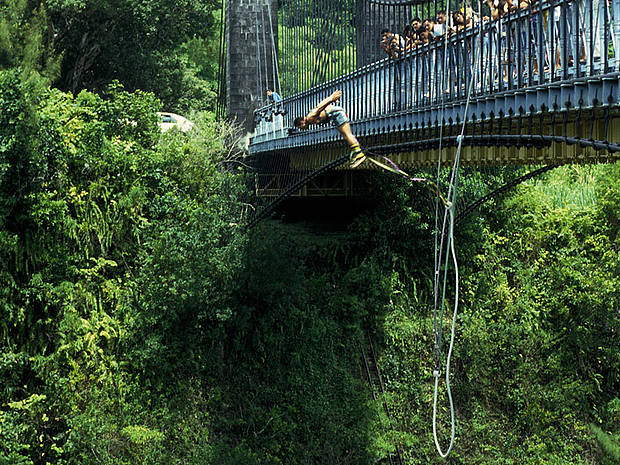 Mensch springt am Bungee-Seil von einer Brücke